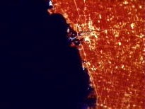 Satellite view showing red heat coming off of dense human development along coastline