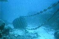 Large heavy chained anchor object dragging through coral on ocean floor